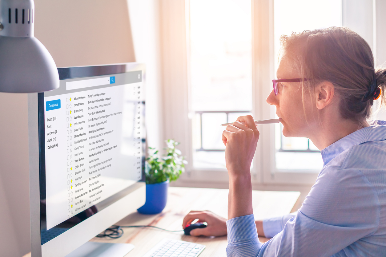 Female business person reading email on computer screen at work